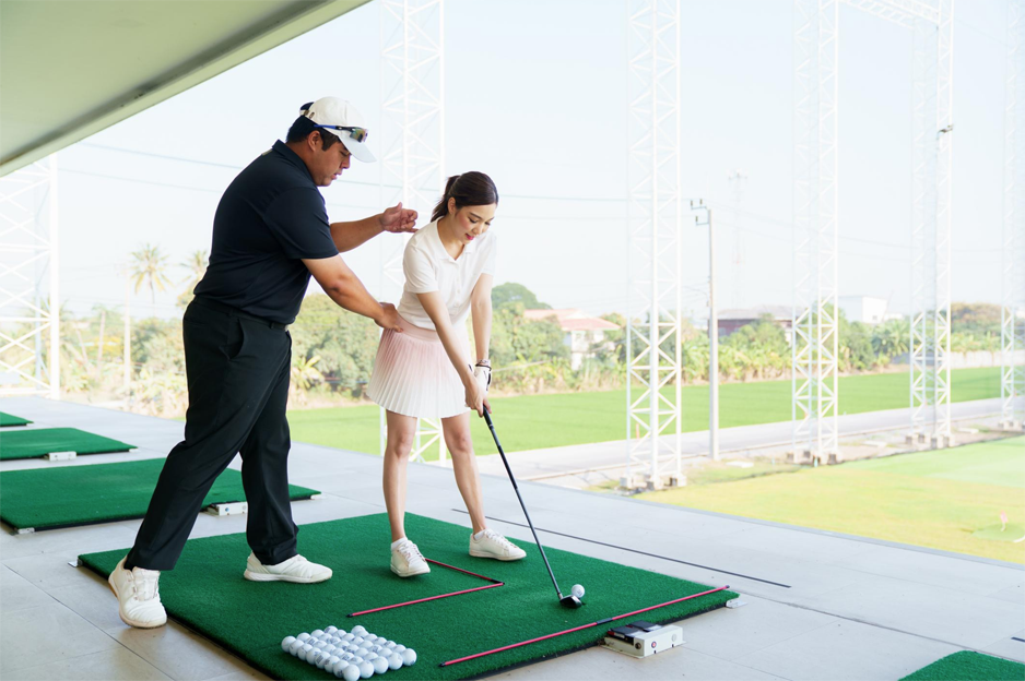 Golf coach observing a player practising a swing and providing technical feedback